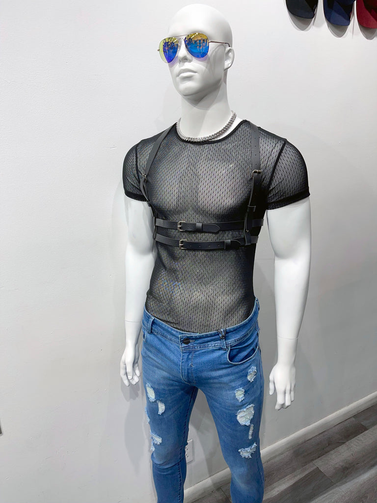 a bald, white mannequin wearing mirrort yellow and blue sunglasses, a rope chain necklace, black mesh t-shirt, black waist harness, and light distressed denim pants.