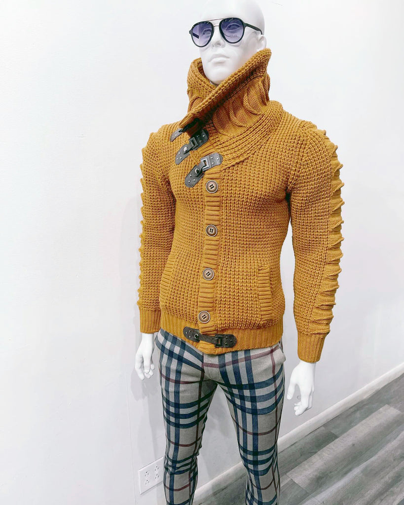 white mannequin wearing sunglasses, a high-collar mustard cardigan sweater, and light brown pants with a black, white and burgundy plaid pattern.