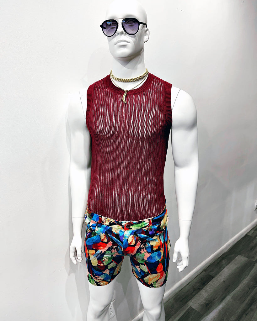a mannequin with violet gradient tint sunglasses, a gold chain necklace, a gold necklace with a gold shark tooth on it, a burgundy open knit tank top, and 5-pocket stretch shorts with a rainbow brush stroke pattern.