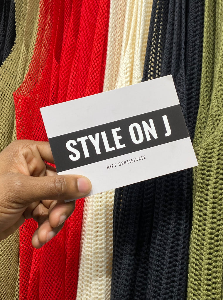 A had holding a Style On J gift card in front of a rack of beige, red, off white, black and khaki green tank tops.s