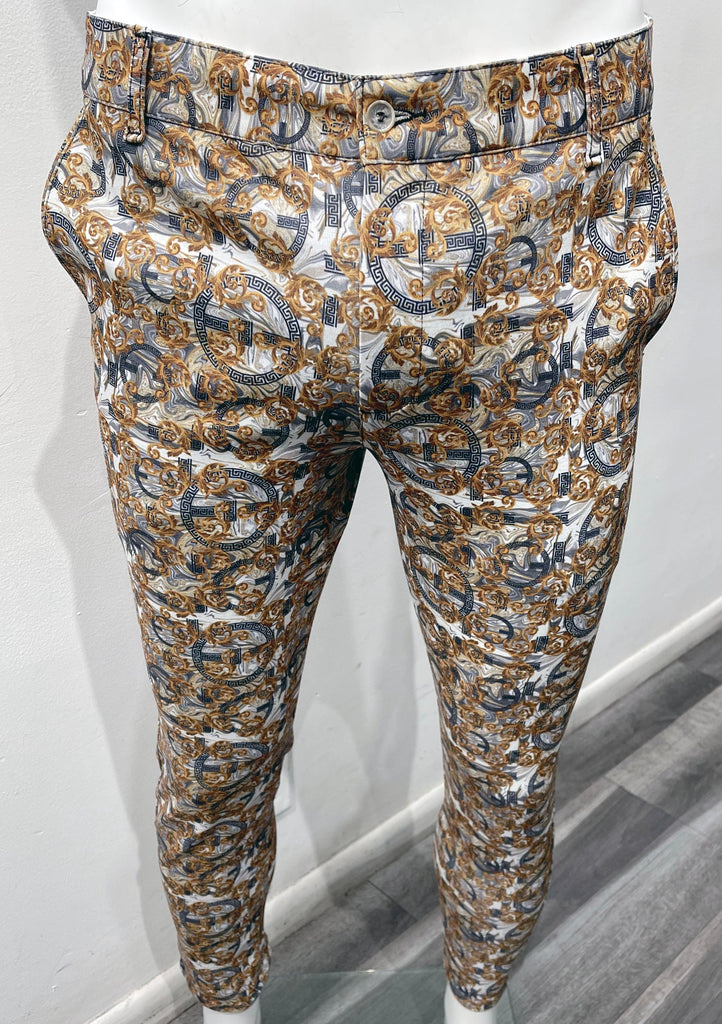 White flat front pants with a dark blue and gold layered ornate pattern, as seen from the front.