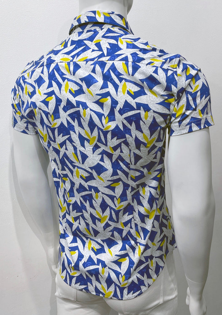   White short-sleeved button down shirt with blue, white and yellow floral and leaves pattern, as seen from the back.