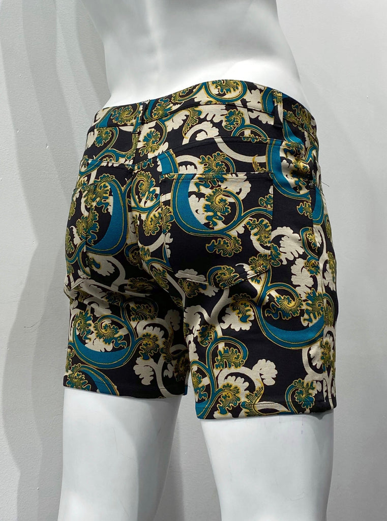 Zip-front, 5-pocket stretch knit shorts it beige, teal and gold calypso floral pattern on a black background, as seen from the back.