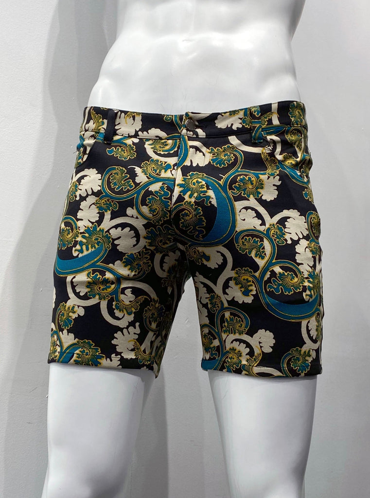 Zip-front, 5-pocket stretch knit shorts it beige, teal and gold calypso floral pattern on a black background, as seen from the front.