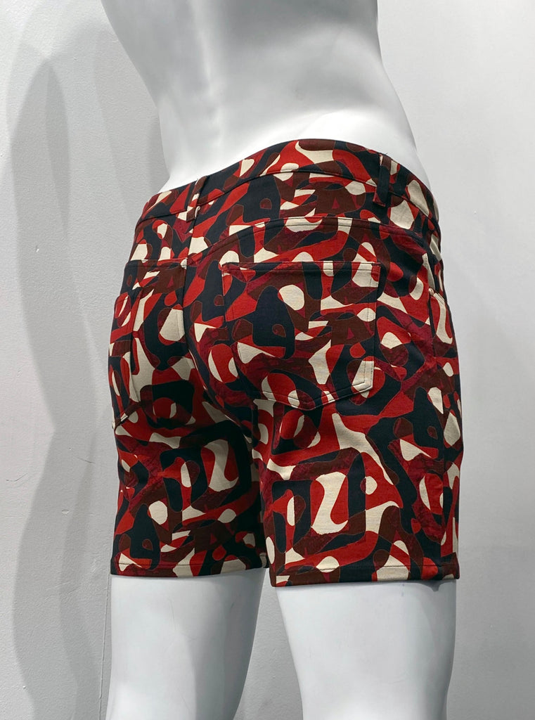 Zip-front, 5-pocket stretch knit shorts with beige, poppy red, and black mod pattern of overlaying rings of different shapes and thicknesses, as seen from the back.