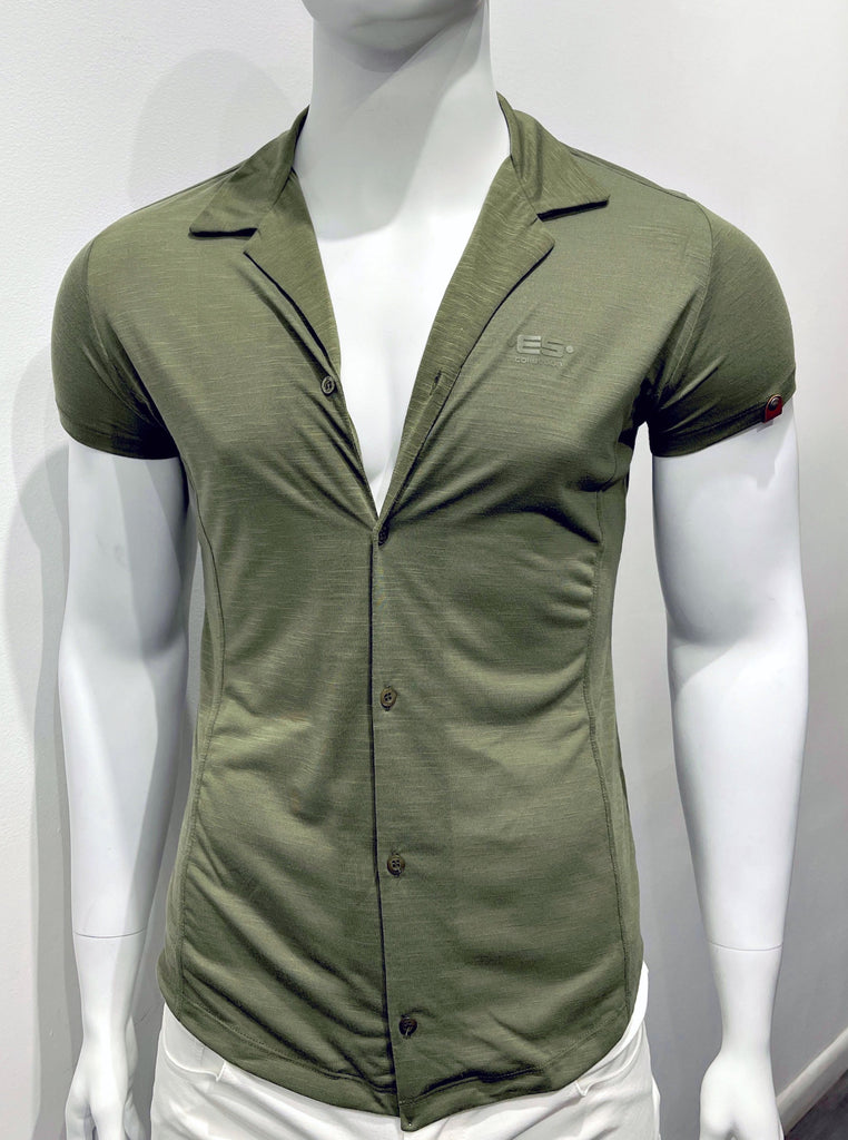 Khaki green short-sleeved button-down collared shirt with khaki green buttons as seen from the front. There is a small brown leather patch with a round silver snap detail on the front of the left sleeve, and a brand emblem woven into the left breast.