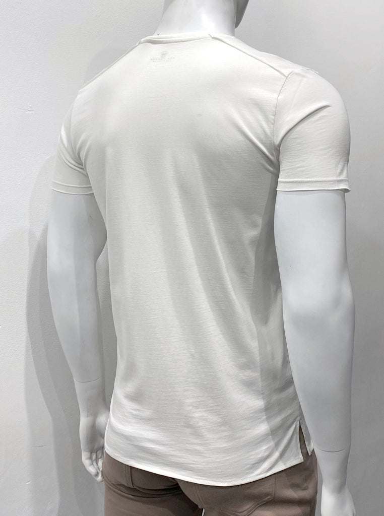Off-white T-shirt with an extended torso length, as seen from the back. The hem is split on the sides and about an inch lower in back than in the front.