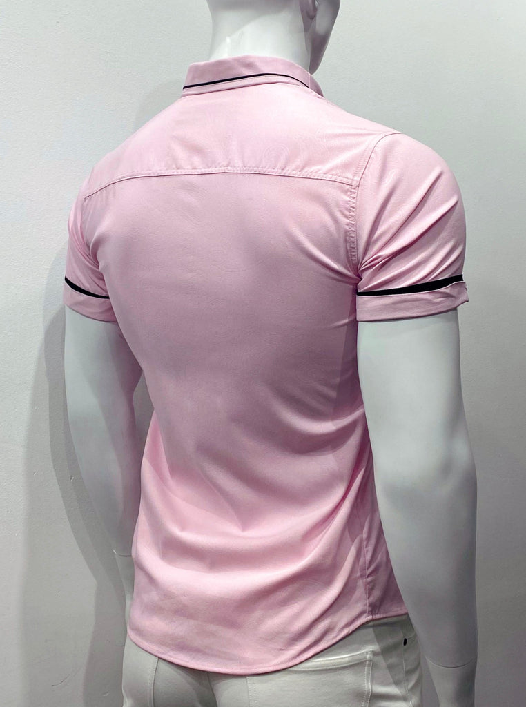 Pink short-sleeved button down shirt as seen from the back. The back side of the navy blue sleeve cuffs are covered with an additional cuff of the pink fabric that encircles just the back side of the arm holes and covers up most of the navy blue arm cuffs, so just a sliver of navy blue  is visible over the pink cuffs. There is a subtle paisley pattern woven into the pink fabric. The fabric on the inside back of the collar is navy blue, so it just peeks out from underneath the pink collar.