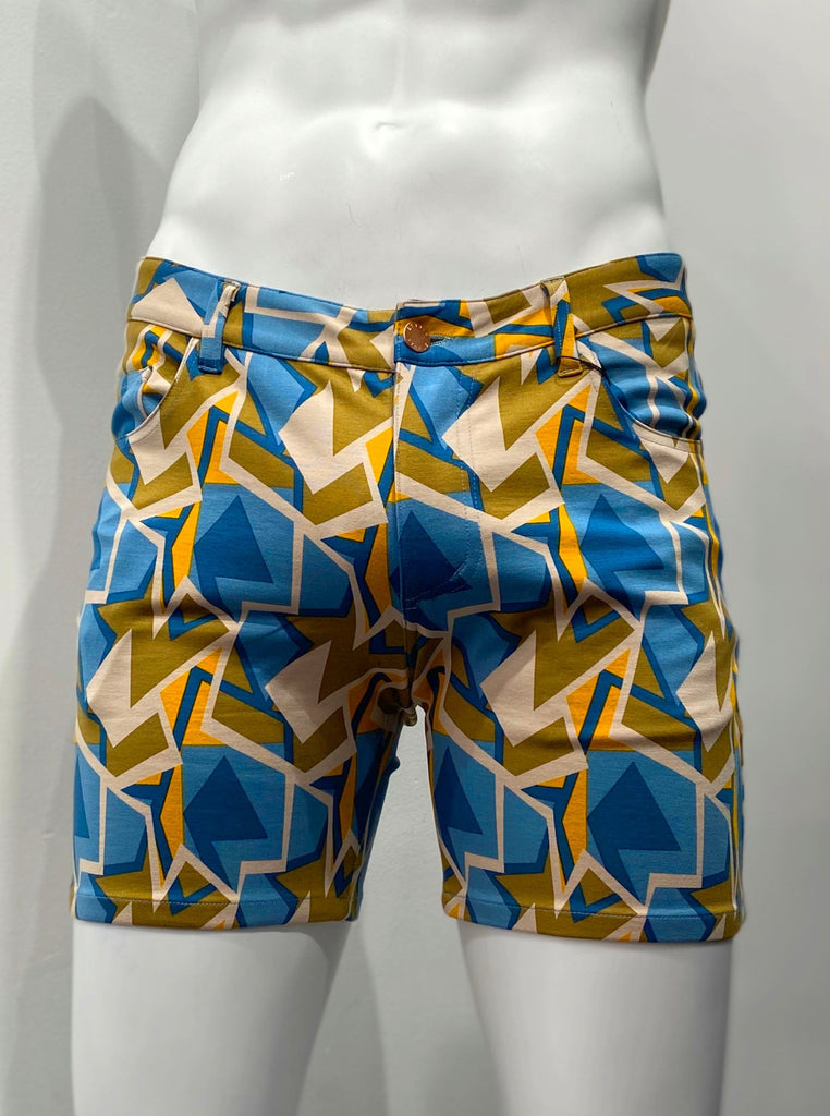 Zip-front, 5-pocket stretch knit shorts as seen from the front, covered with an angular teal, beige, khaki green, navy blue, and orange mosaic pattern.