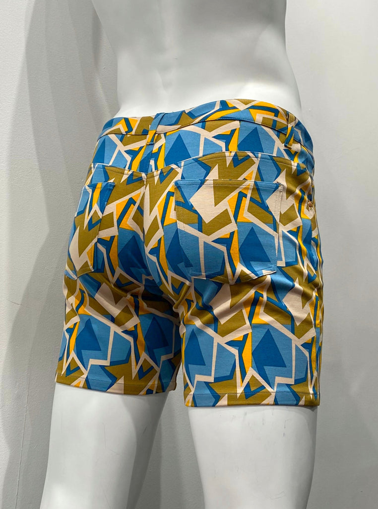 Zip-front, 5-pocket stretch knit shorts as seen from the back, covered with an angular teal, beige, khaki green, navy blue, and orange mosaic pattern.