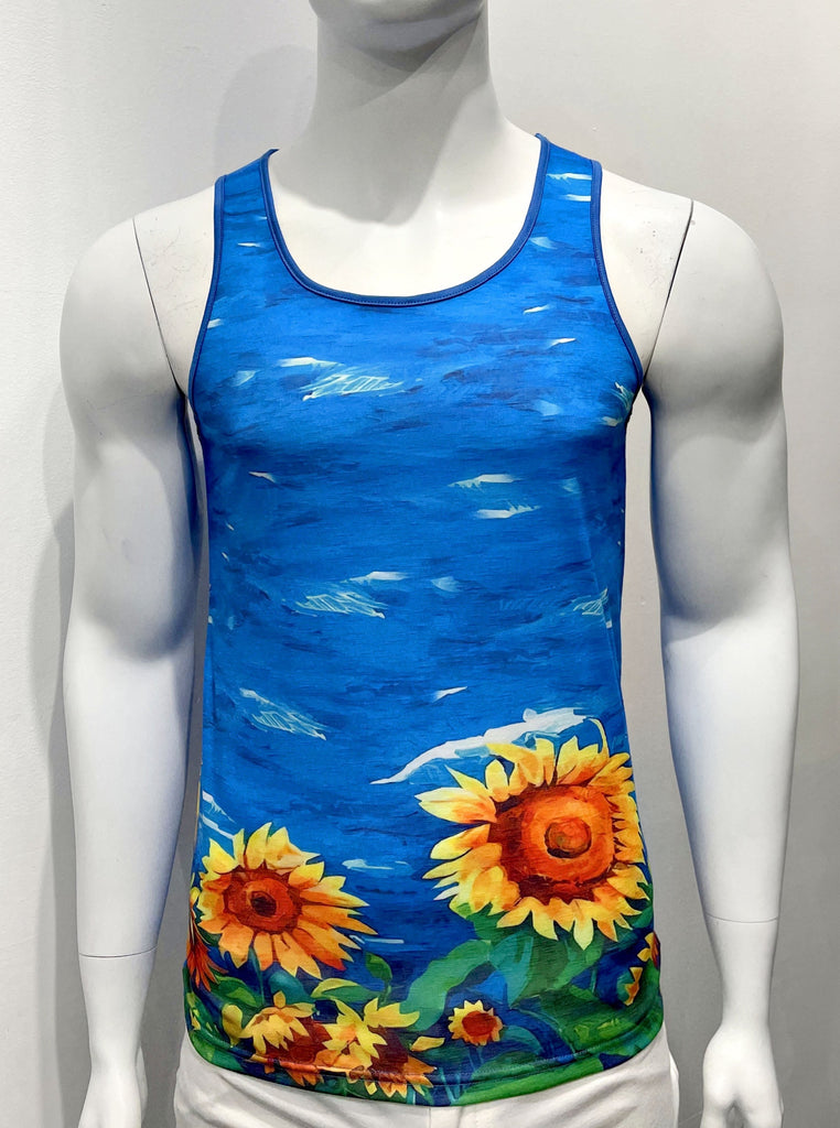  Tank top as seen from the front. It is covered with a colorful graphic print of royal blue water with bold, yellow and orange colored sunflowers along the bottom of the tank top. There is blue piping on both sides of the shoulder straps.