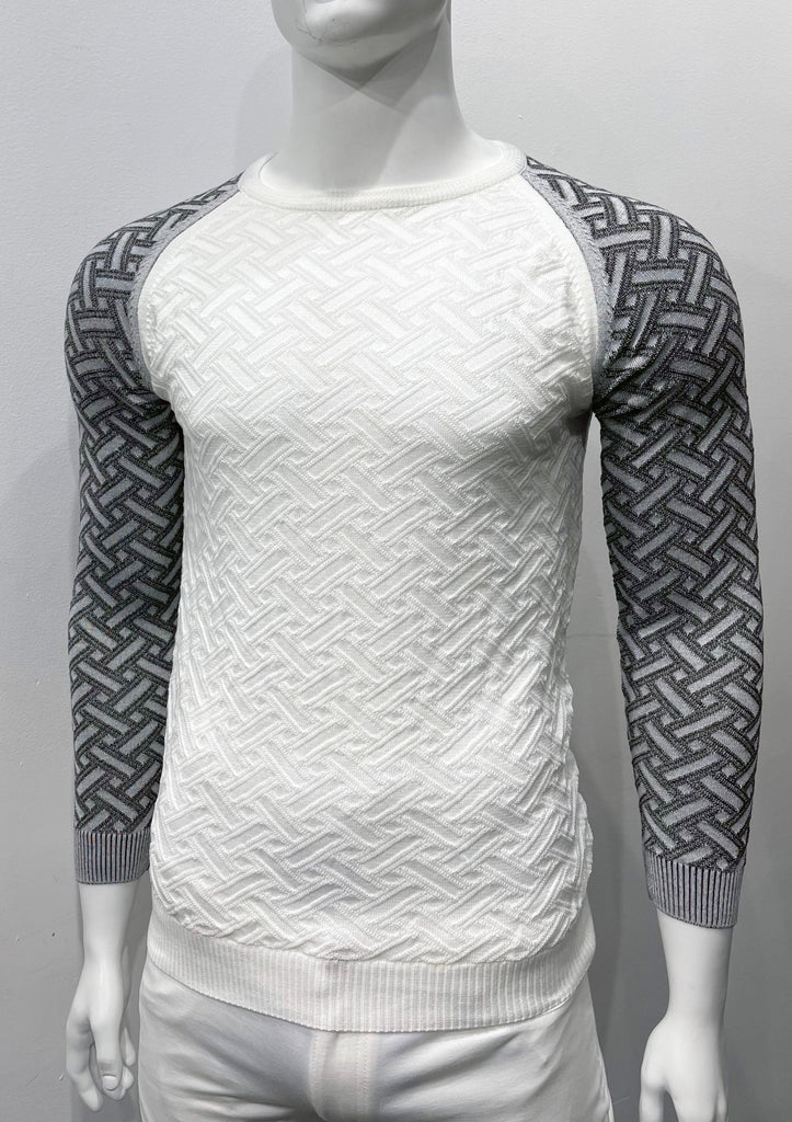Black and white crew neck, raglan-sleeve sweater as seen from the front. The torso is white with a geometric weave patter woven into the knit fabric. The sleeves are charcoal with lighter great geometric weave pattern woven into the knit fabric.