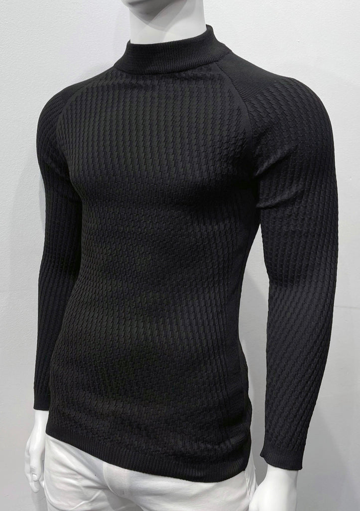 Black long-sleeve, turtleneck sweater with raglan sleeve design as seen from the front. There is a waffle weave pattern woven into the knit fabric.