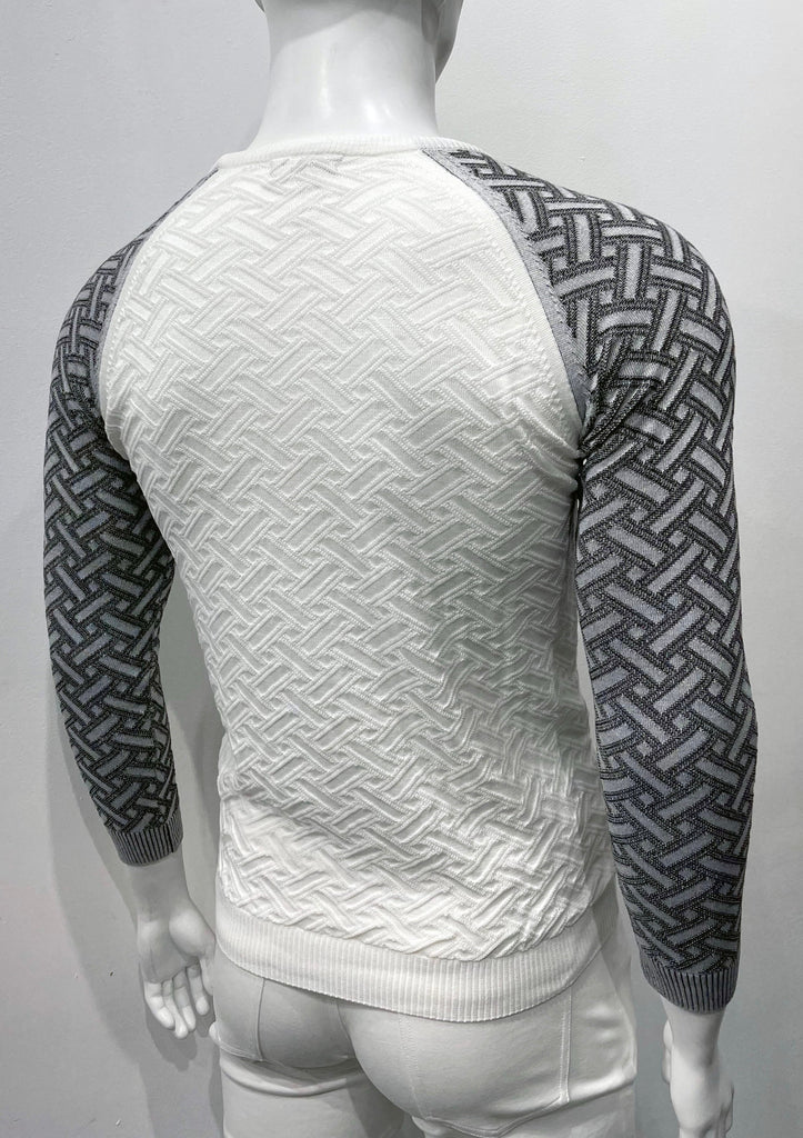 Black and white crew neck, raglan-sleeve sweater as seen from the back. The torso is white with a geometric weave patter woven into the knit fabric. The sleeves are charcoal with lighter great geometric weave pattern woven into the knit fabric.
