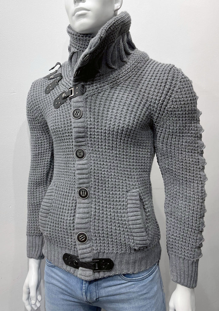 Dark grey high-collared cardigan sweater as seen from the front, with large dark grey buttons, a grey leather latch and strap fastener in place of the top button, two grey leather strap and latch details on the right breast, and grey latch and strap detail center-front along the hem