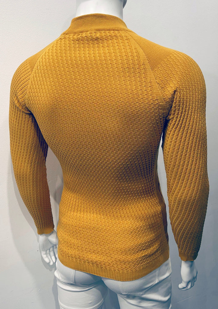 Golden long-sleeve, turtleneck sweater with raglan sleeve design as seen from the back. There is a waffle weave pattern woven into the knit fabric.