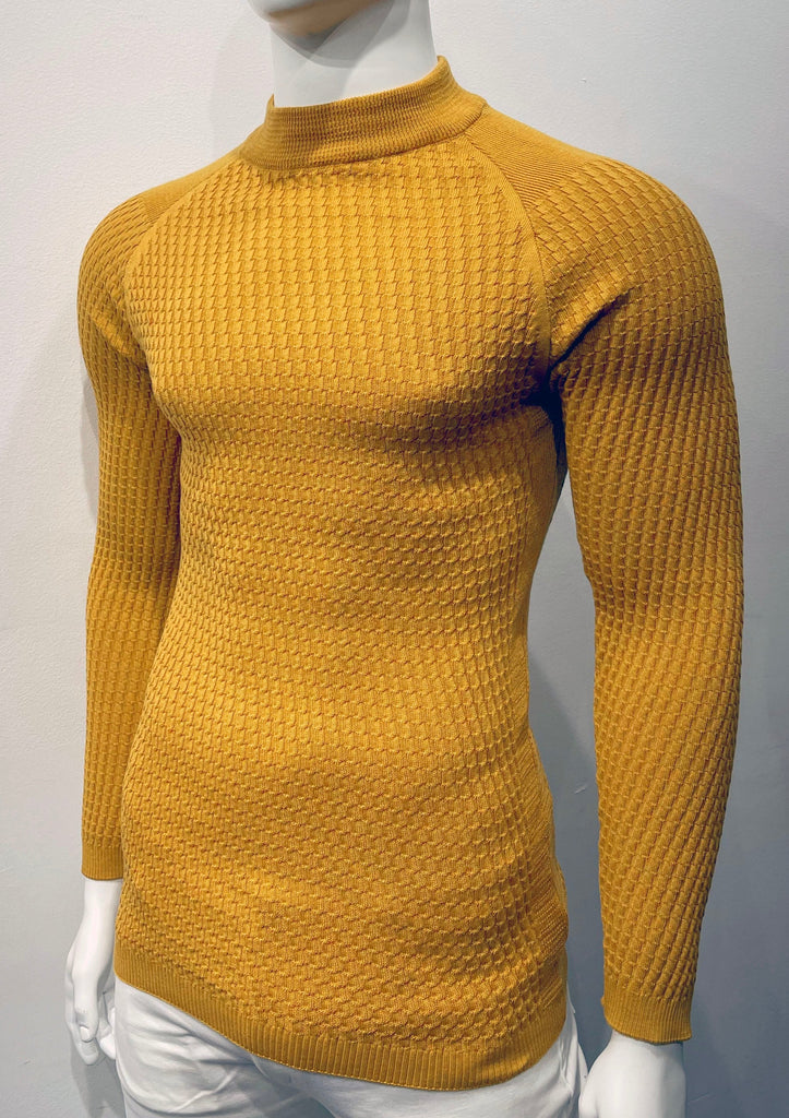 Golden long-sleeve, turtleneck sweater with raglan sleeve design as seen from the front. There is a waffle weave pattern woven into the knit fabric.