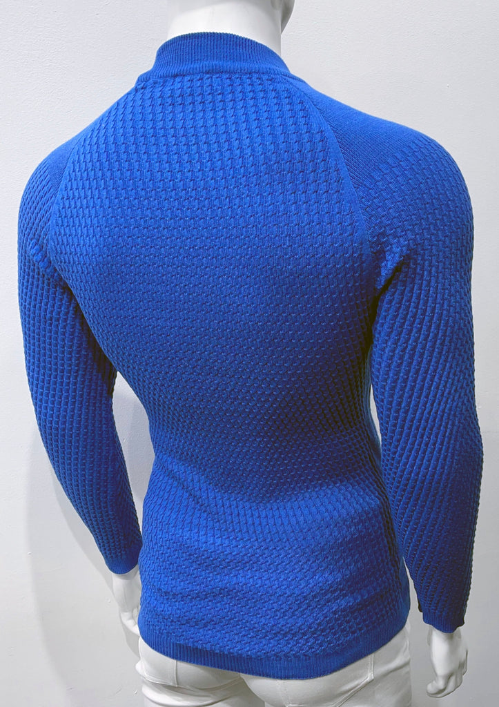 Royal blue long-sleeve, turtleneck sweater with raglan sleeve design as seen from the back. There is a waffle weave pattern woven into the knit fabric.