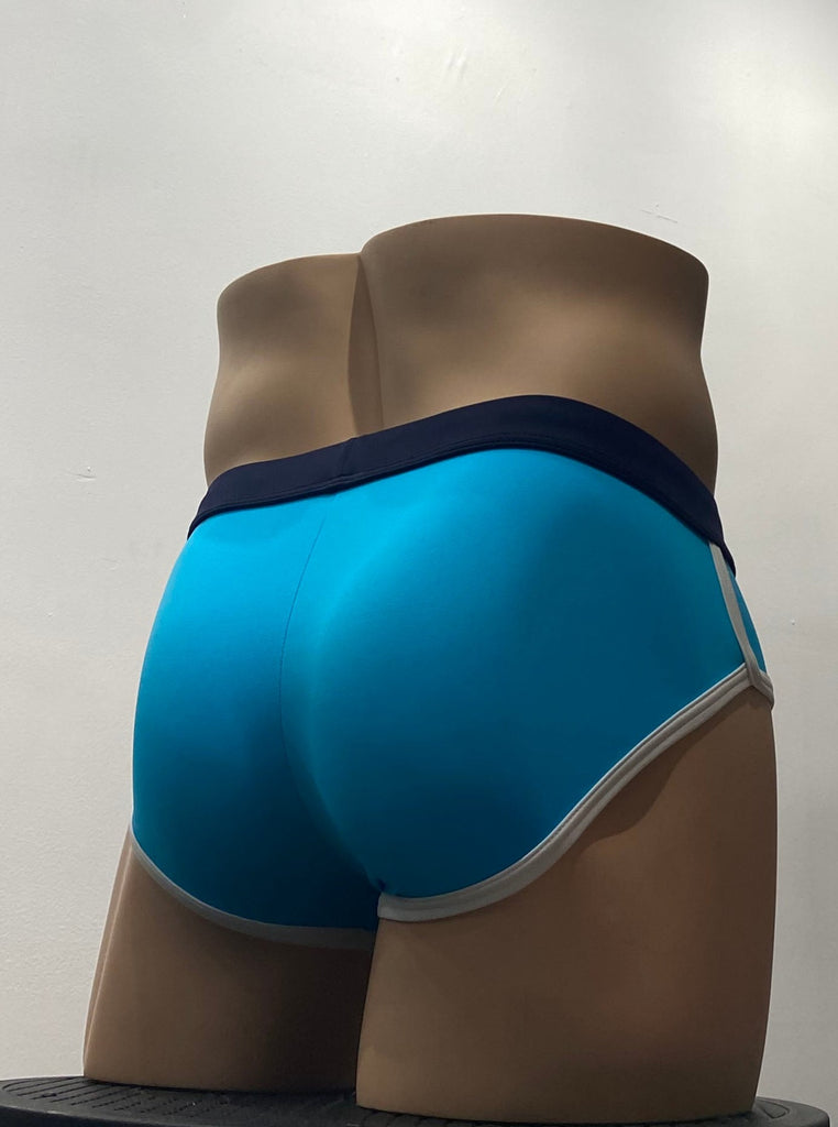 Turquoise swim brief as seen from the back, with a navy blue waistband and white piping around the leg openings.