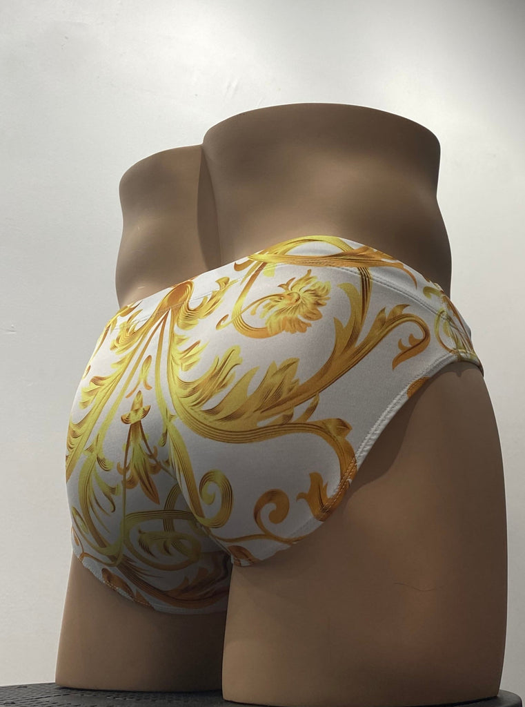 White swim brief as seen from the back, with gold deco design on it.